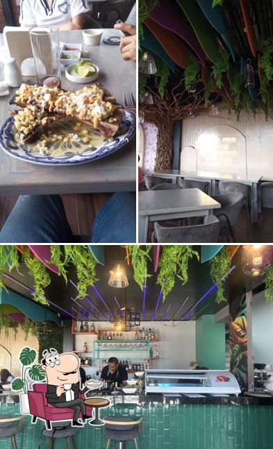 Mesas, sillas, árbol decorativo y vegetación del interior de Qué Agonía.